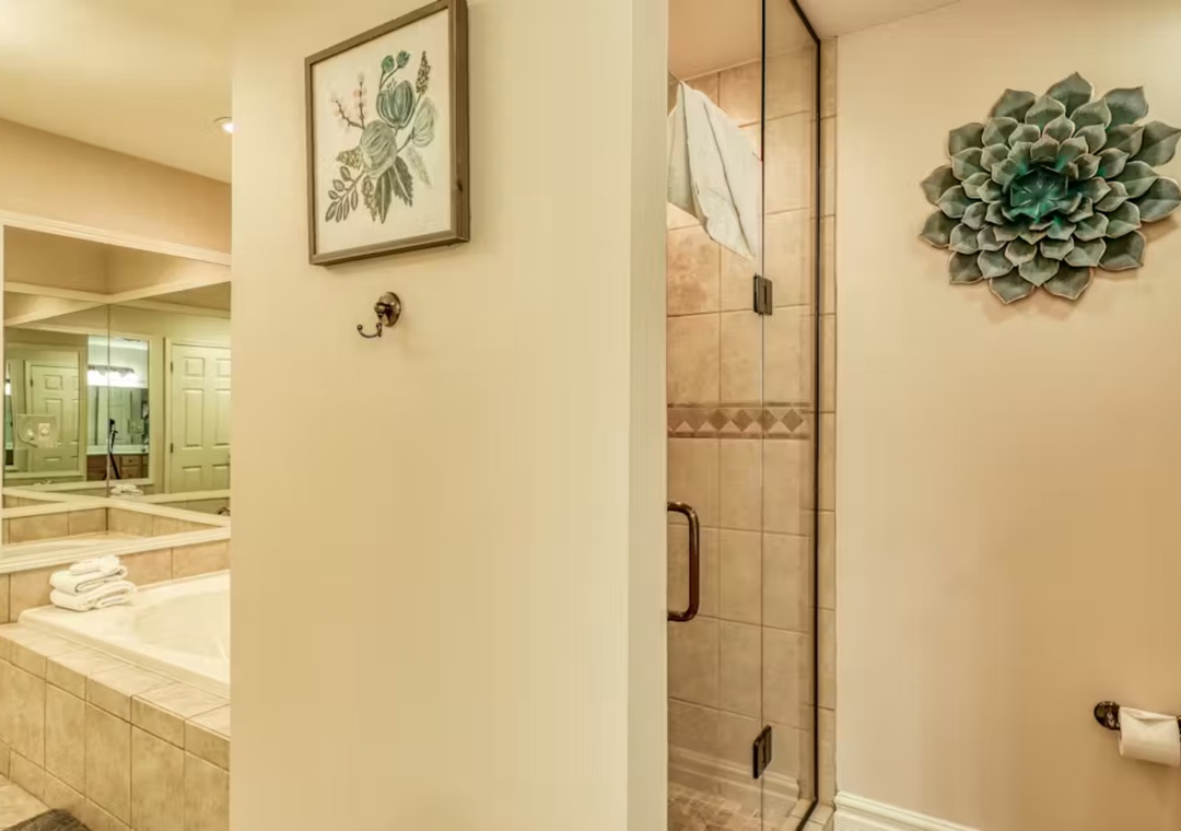 Unwind in your elegant bathroom featuring a glass shower, decorative botanical artwork, and luxurious spa-like ambiance.