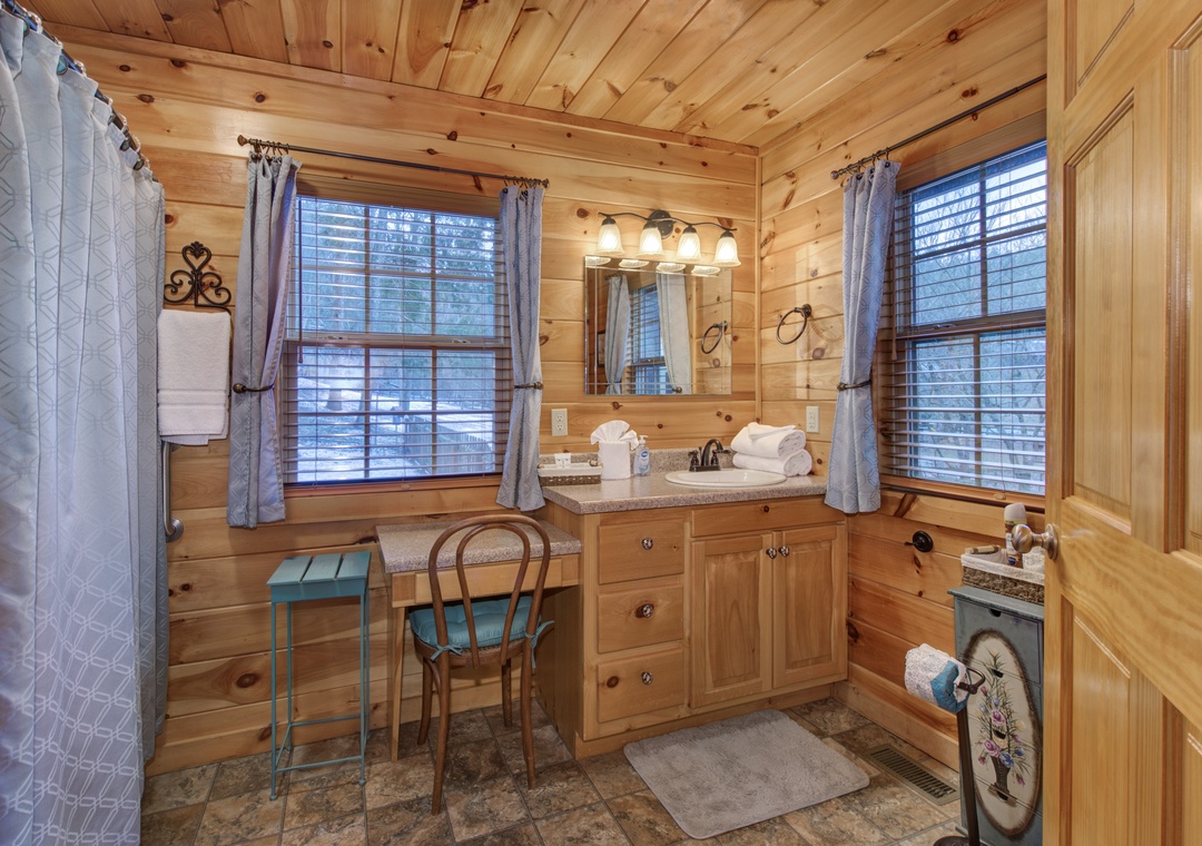 Unwind in your rustic bathroom with warm wood accents, granite counters, and natural light streaming through windows.
