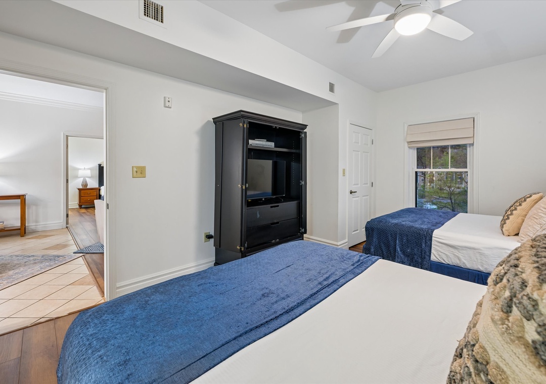 Relax in your serene bedroom with twin beds dressed in plush blue linens, complete with entertainment center and ceiling fan for your comfort.