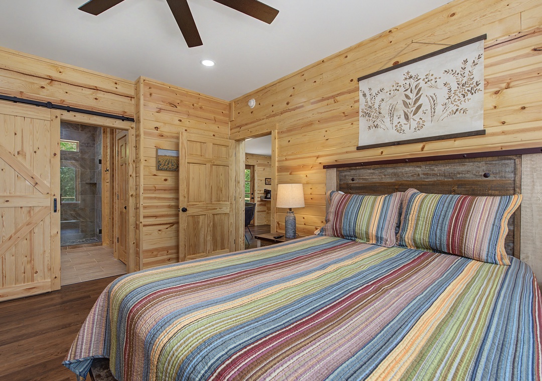 Sink into the plush bed beneath vaulted ceilings and warm pine walls, where colorful linens and rustic charm create your perfect retreat after a day of adventure.