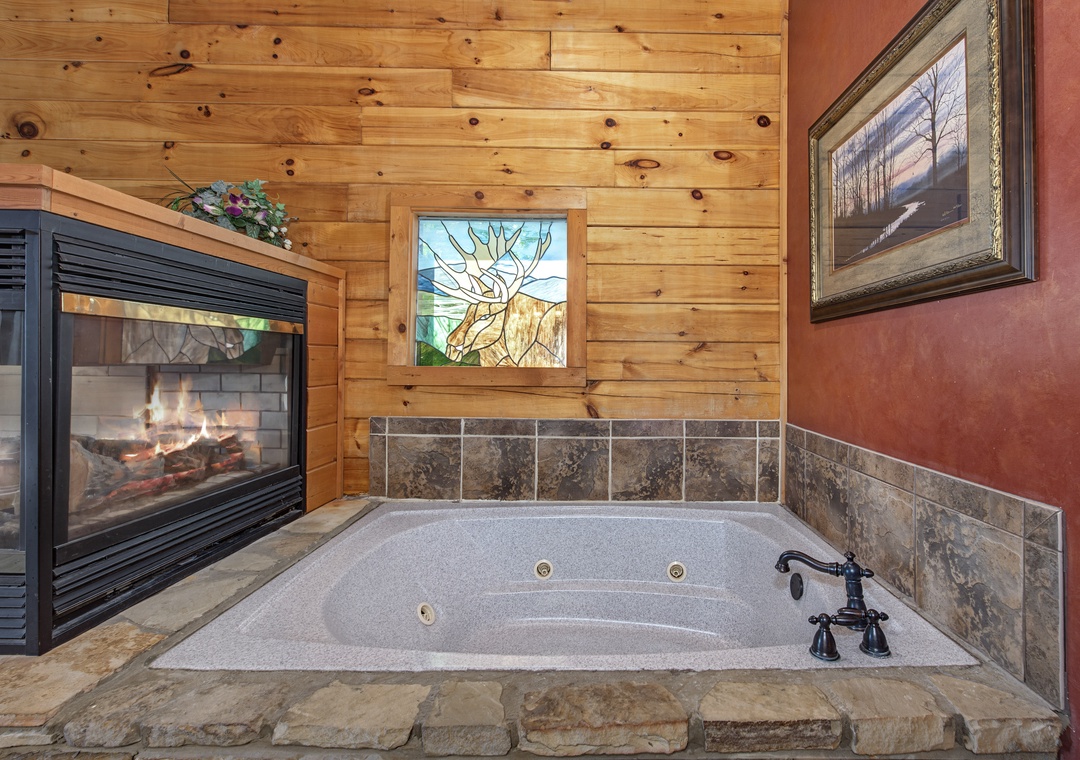 Sink into your private jetted tub beside a warm glowing fireplace—rustic wood walls, stone tile, and mountain-inspired decor create the ultimate cozy escape.