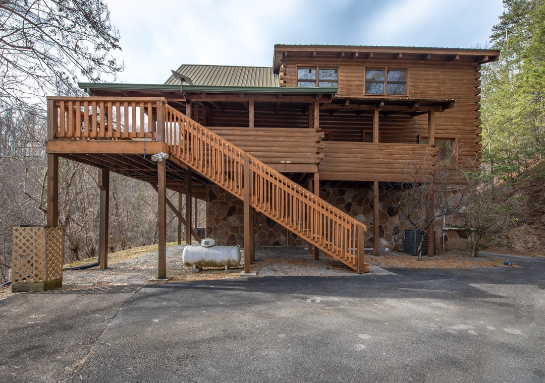 Rustic log cabin retreat nestled among trees with convenient parking and elevated deck access for mountain getaway comfort.