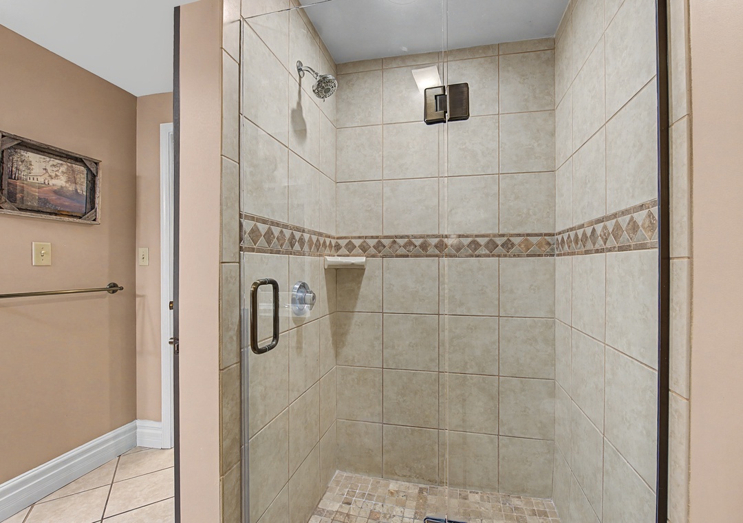 Step into your elegant tiled shower with glass doors and decorative accent border - perfect for refreshing after adventures.