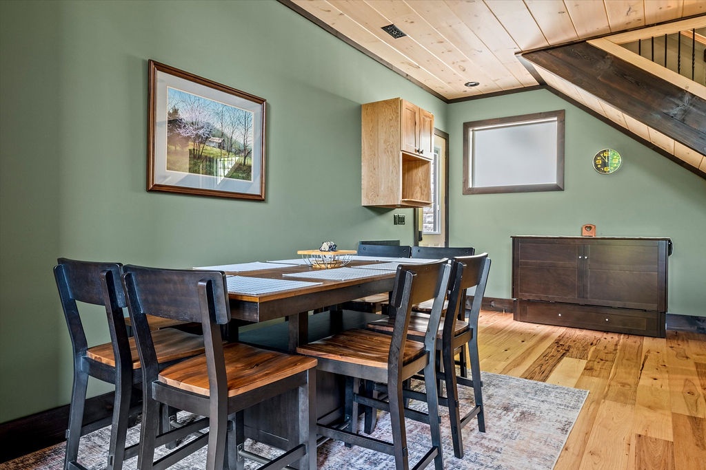 Gather around this inviting dining table where your group can share meals and make memories. The warm wood tones and soft green walls create a cozy mountain retreat atmosphere.