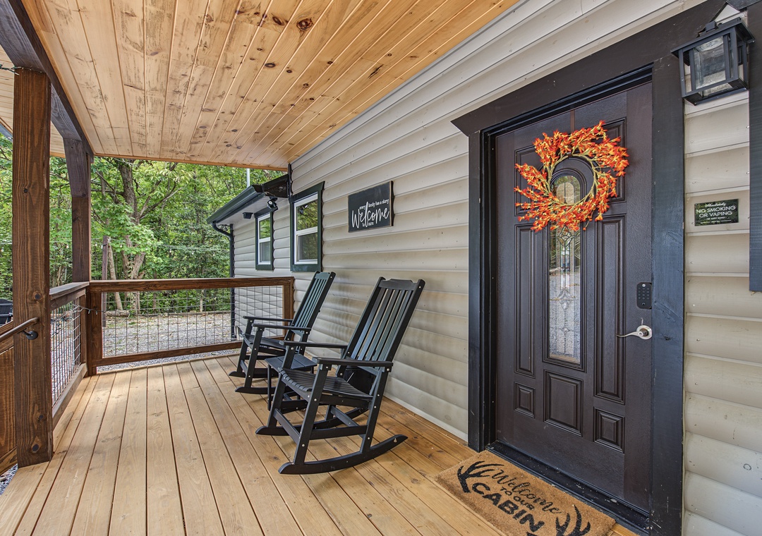 A charming covered porch with rustic wood finishes and a welcoming seasonal wreath invites guests to relax in the rocking chairs before stepping inside.