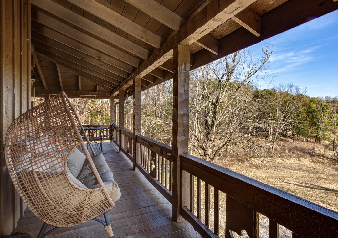 Unwind in your private hanging chair on this peaceful balcony, where rustic wood beams frame serene forest views.