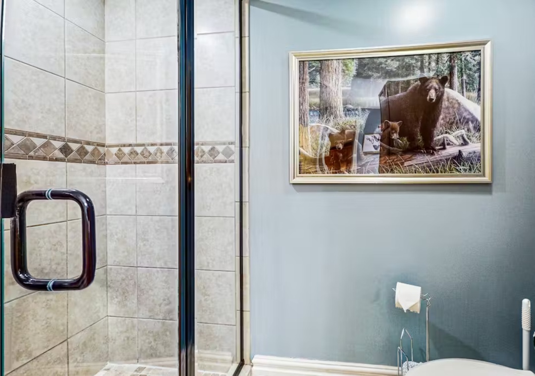 Your private bathroom features a spacious glass shower with elegant tile work and charming woodland artwork that creates a peaceful retreat.