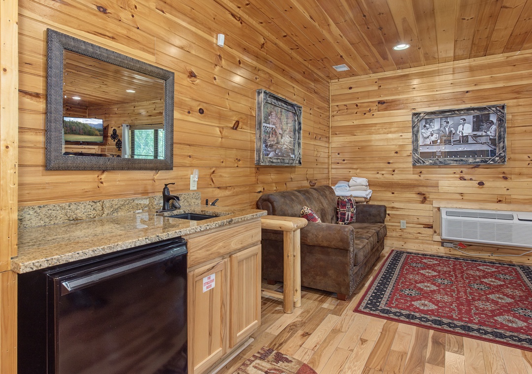 Unwind in your rustic retreat with warm wood walls, cozy seating, and a convenient kitchenette for your mountain getaway comfort.