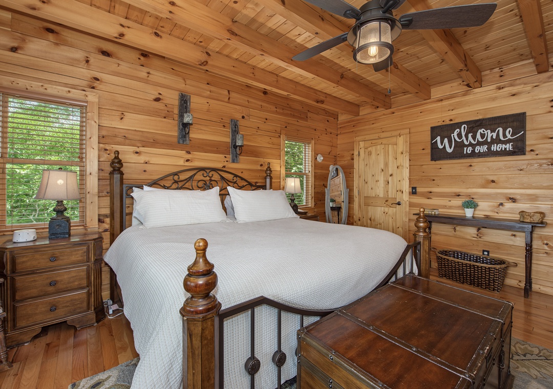 Step into your cozy mountain retreat with warm wood beams overhead, plush bedding, and natural light streaming through the windows, inviting you to unwind.