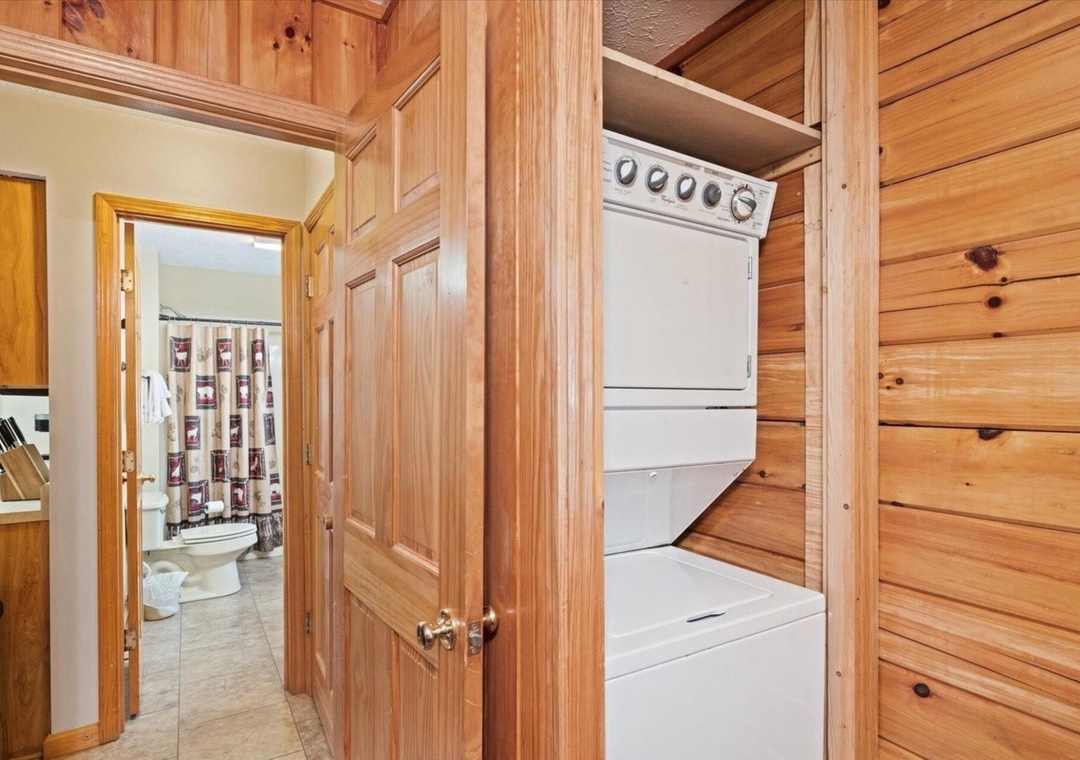 Your private laundry facilities feature a convenient washer-dryer combo, tucked away behind custom wood cabinetry for a seamlessly organized space.