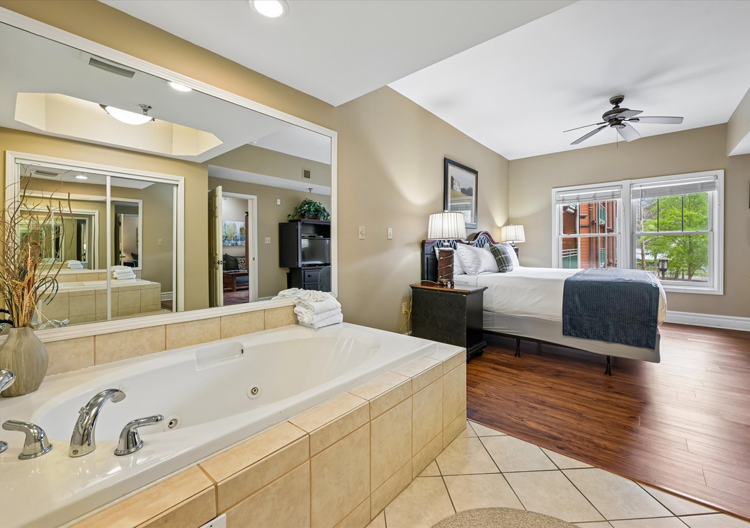 Unwind in your spacious bedroom featuring a luxurious jetted tub, perfect for romantic soaks while enjoying city views through large windows.