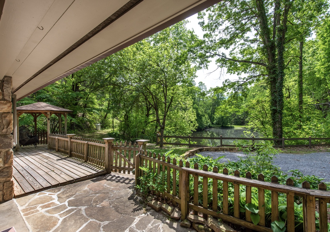 Covered patio with wooded views and easy access to a gazebo, perfect for relaxing in the fresh air amid lush greenery.