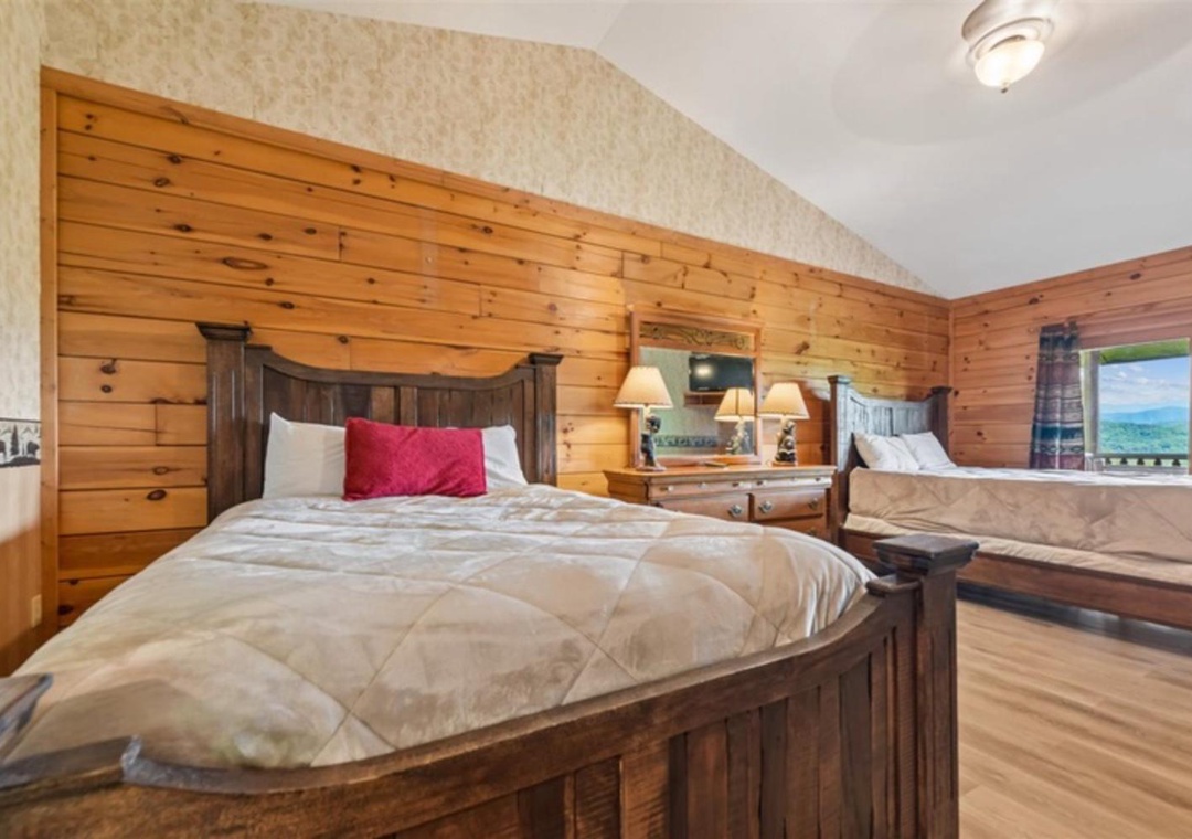 Drift off in cozy comfort beneath soaring ceilings and warm knotty pine walls, with peaceful mountain views framed by your window—your restful retreat awaits.