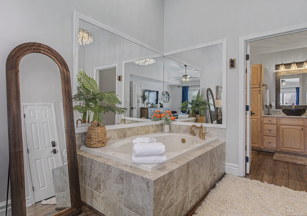 Luxurious marble soaking tub awaits your relaxation, surrounded by elegant mirrors and tropical touches for ultimate spa vibes.