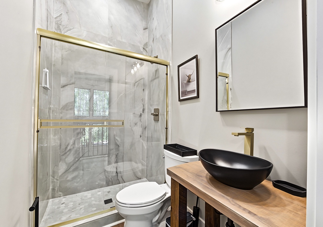 Step into your sleek, modern bathroom with a luxurious marble-tiled shower and elegant black vessel sink atop warm wood—crafted for your ultimate comfort and style.
