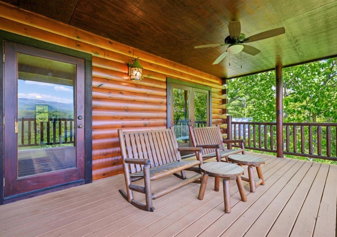 Relax on your private covered deck with rocking chairs surrounded by lush trees. Enjoy the mountain breeze under the ceiling fan while taking in peaceful forest views.