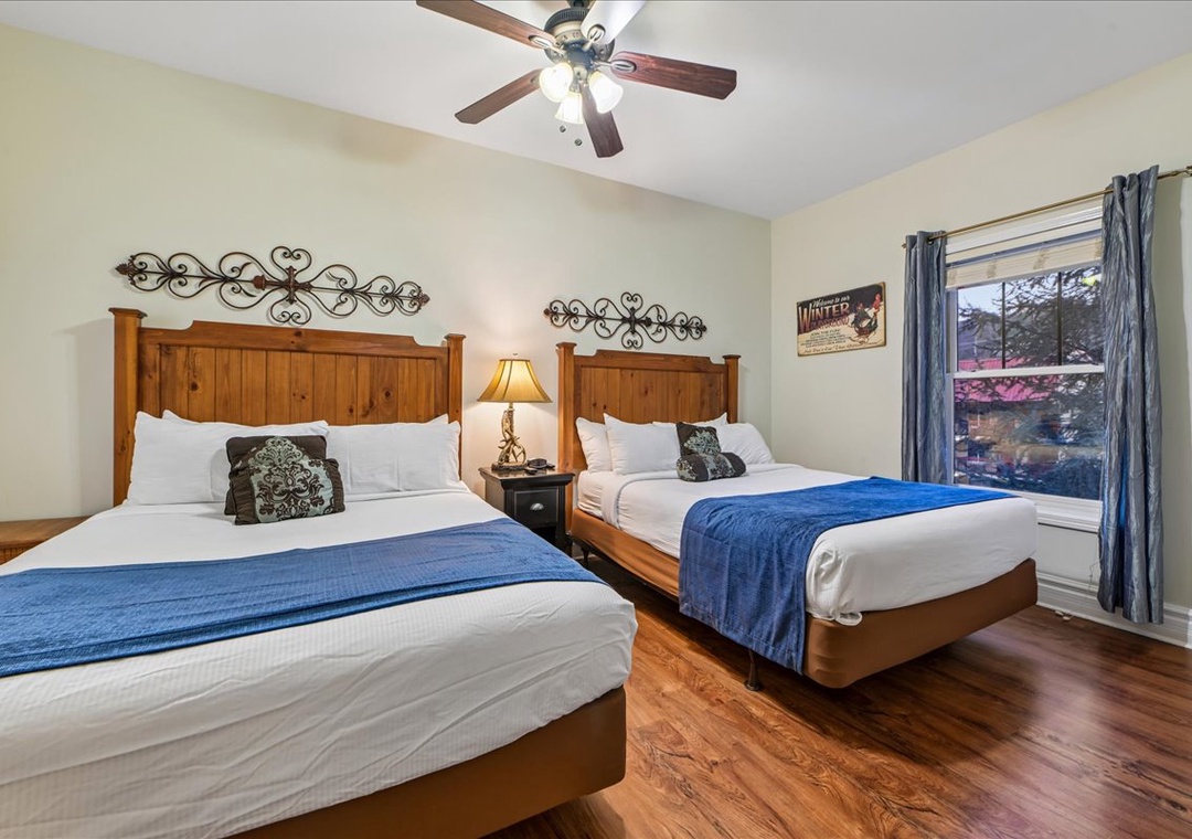 Unwind in your spacious twin bedroom with rustic wooden beds, crisp linens, and blue accent throws creating a cozy mountain retreat atmosphere.
