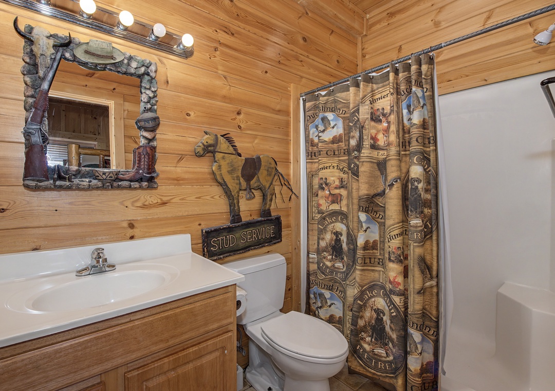 Enjoy your private rustic bathroom with charming wildlife décor, full shower-tub combo, and authentic cabin atmosphere.