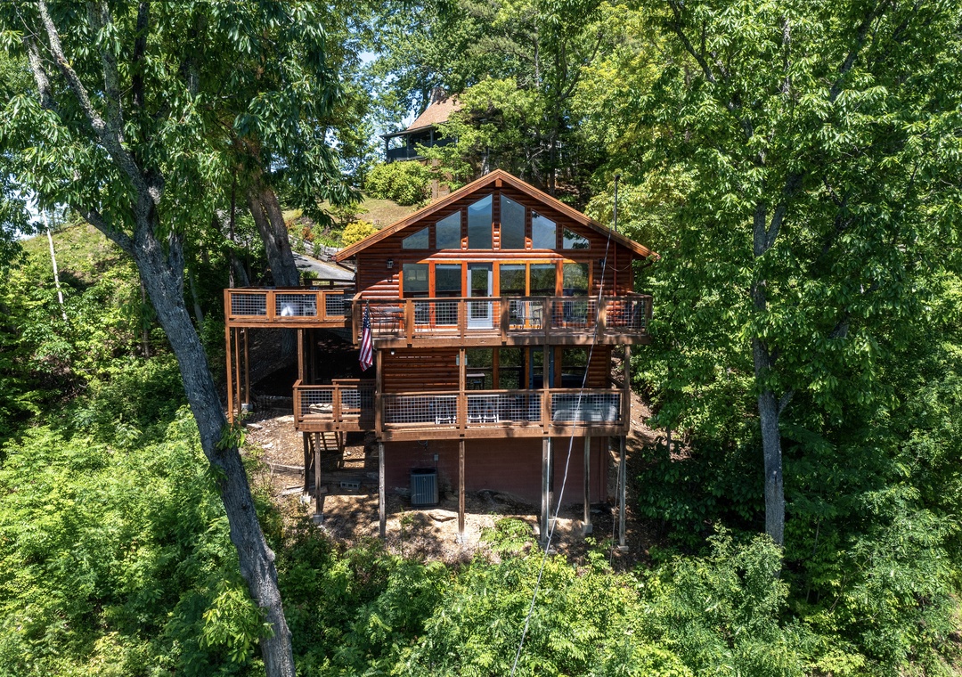 A stunning log cabin nestled among towering trees, featuring expansive decks perfect for morning coffee or evening gatherings, all embraced by nature's lush canopy.