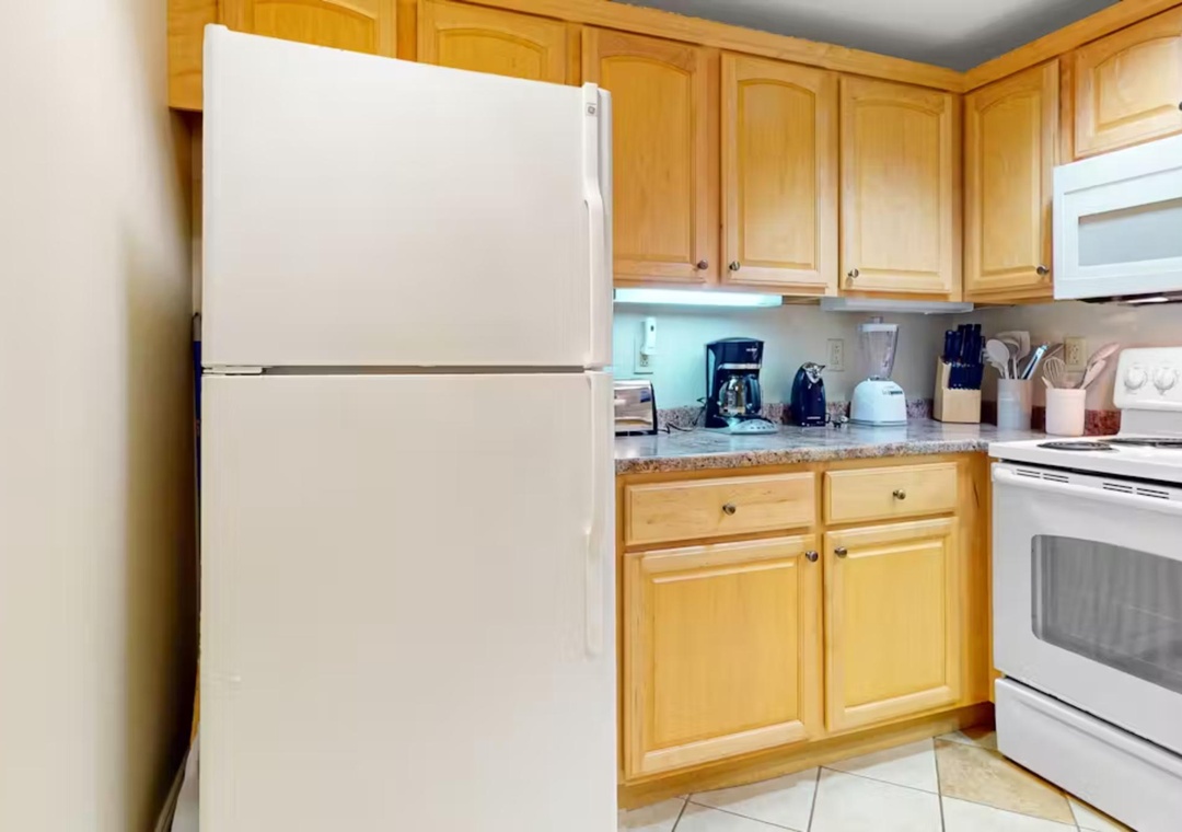 Your fully equipped kitchen features everything needed for home-cooked meals, with warm wood cabinets and modern appliances creating the perfect culinary retreat.