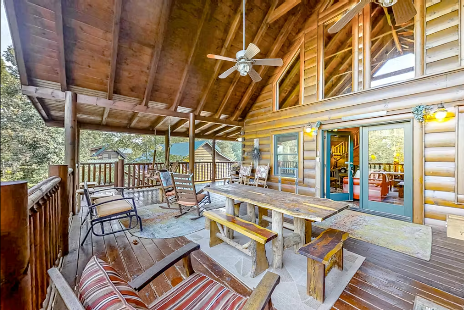 Your private covered deck offers rustic dining with handcrafted furniture, rocking chairs for relaxation, and forest views through tall windows.