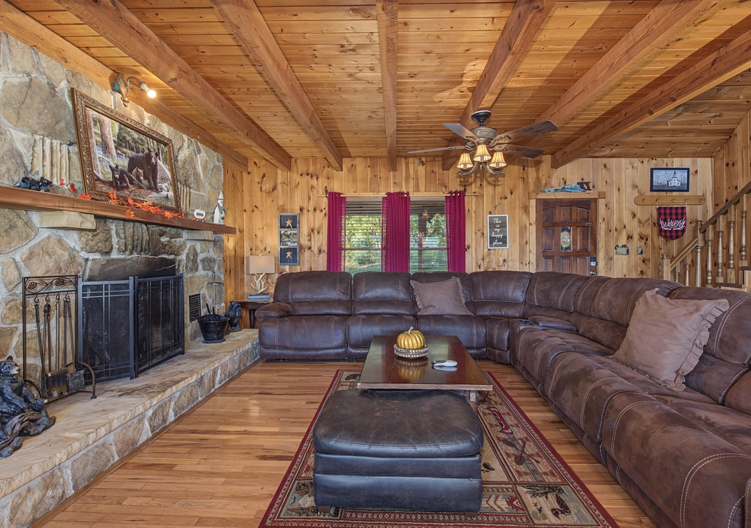 Sink into plush leather seating by the stone fireplace, where exposed wood beams and warm knotty pine create your perfect cabin retreat.