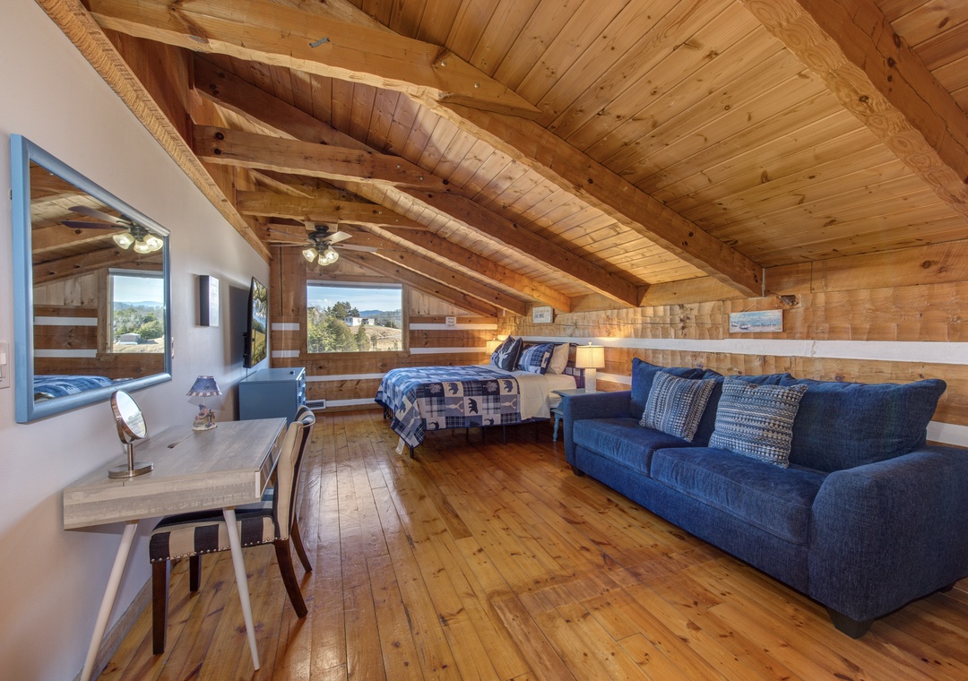 Your cozy loft sanctuary awaits with rustic wood beams, a plush sofa, and peaceful mountain views from every window.