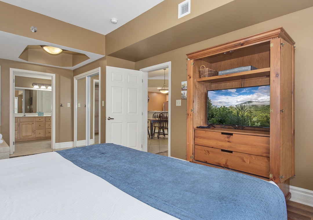 Your spacious bedroom features elegant wood furnishings, a wall-mounted TV for entertainment, and an en-suite bathroom for complete privacy and comfort.