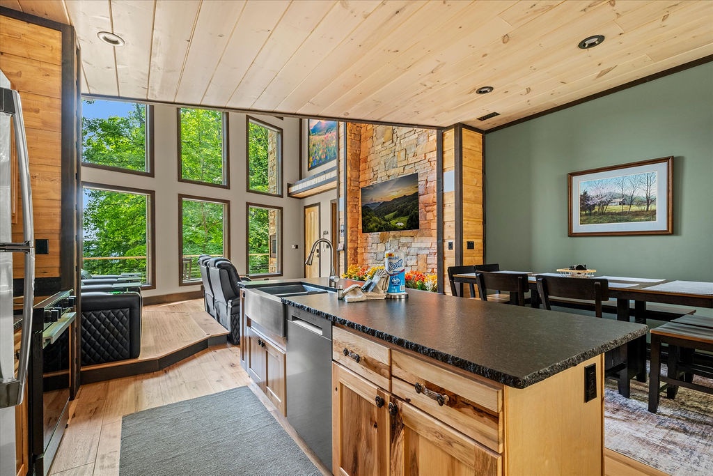 Stunning natural light floods your open-concept kitchen and dining space through soaring windows framing lush forest views. Enjoy preparing meals at the sleek island while soaking in the serene surroundings and modern mountain charm.