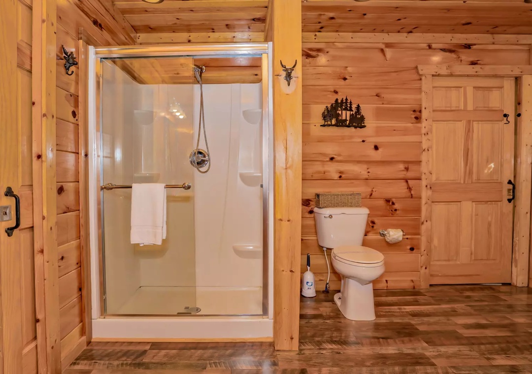 Step into your rustic bathroom featuring rich wood walls and a spacious walk-in shower where you can unwind after mountain adventures.