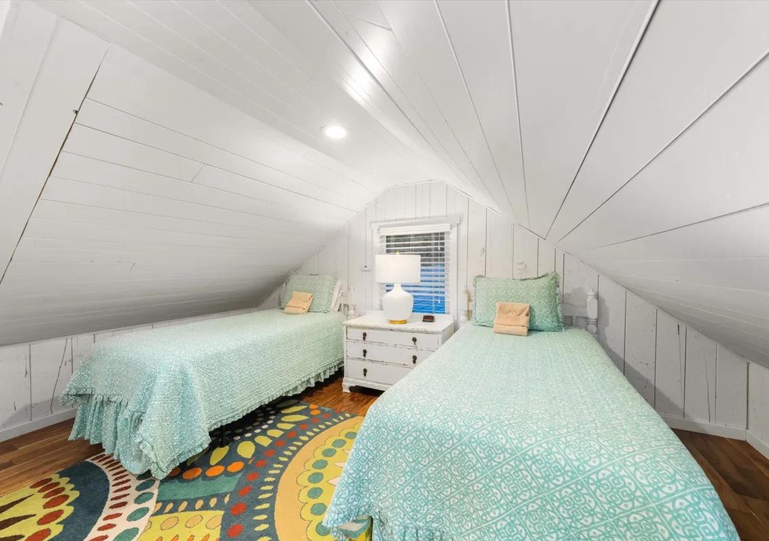 Cozy loft bedroom with twin beds and charming shiplap walls—perfect for kids or guests to unwind after a day of adventure.