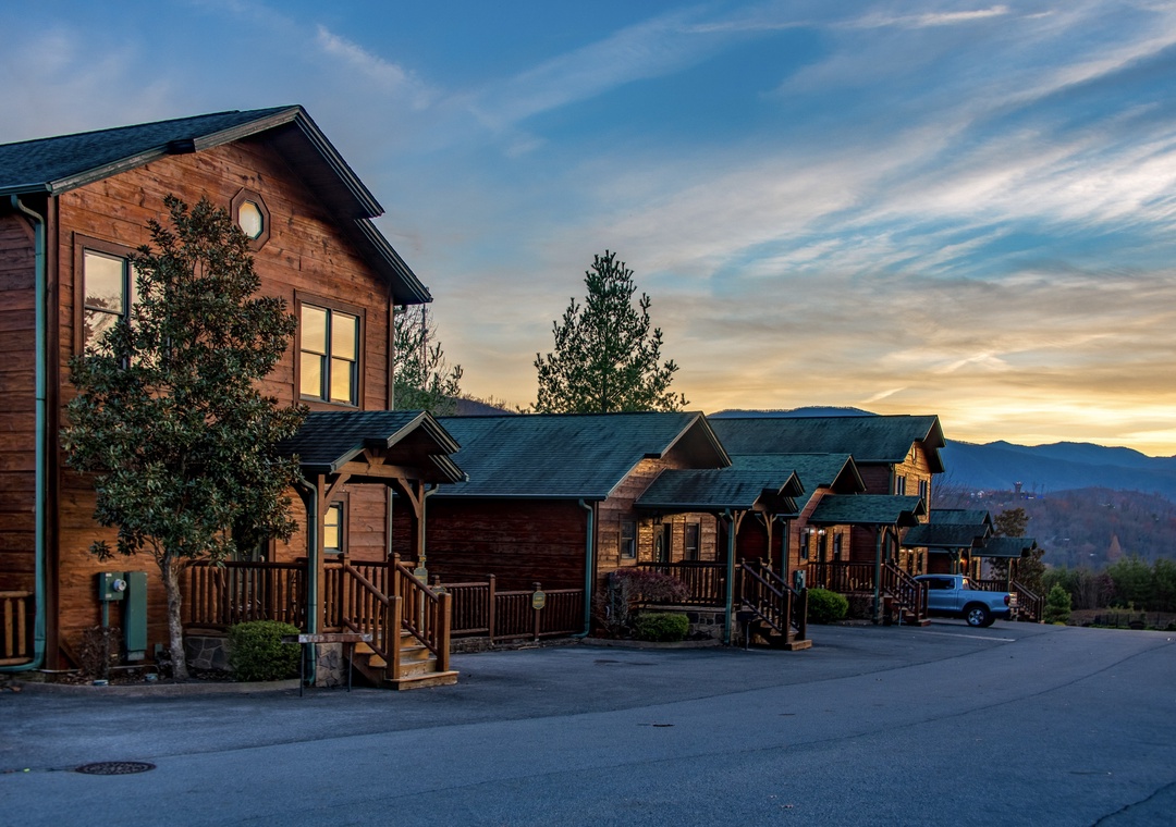 Rustic mountain cabins nestle in the hills at sunset, offering serene views of distant peaks and the perfect retreat from everyday life.