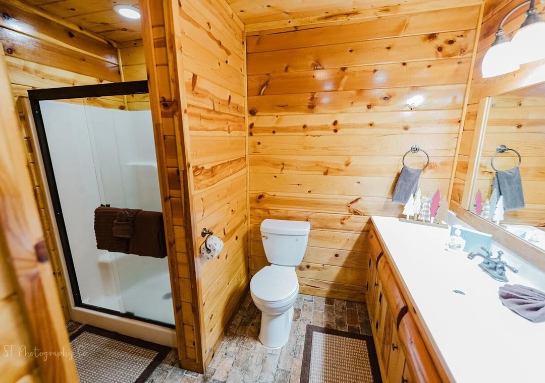 Step into your private cabin bathroom, where warm knotted pine surrounds you with rustic charm. Fresh towels await by the sink, and your spacious walk-in shower promises refreshing mornings.
