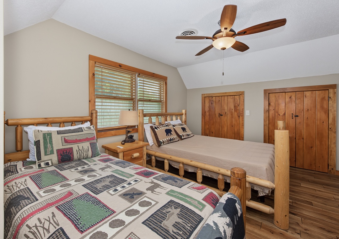 Your cozy retreat awaits with two comfortable log-frame beds dressed in rustic linens. Natural light streams through wooden blinds while the ceiling fan keeps your space perfectly comfortable year-round.