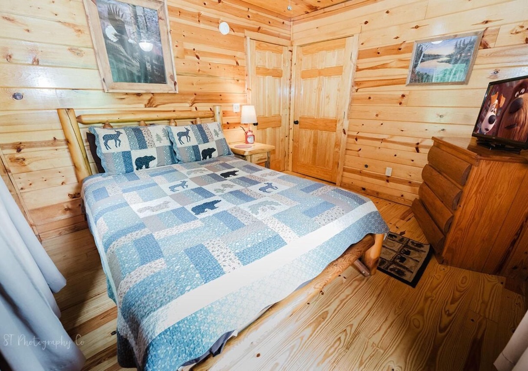 Rustic pine walls and charming wildlife-themed bedding create your cozy mountain retreat, where natural wood and thoughtful details help you unwind after a day of adventure.