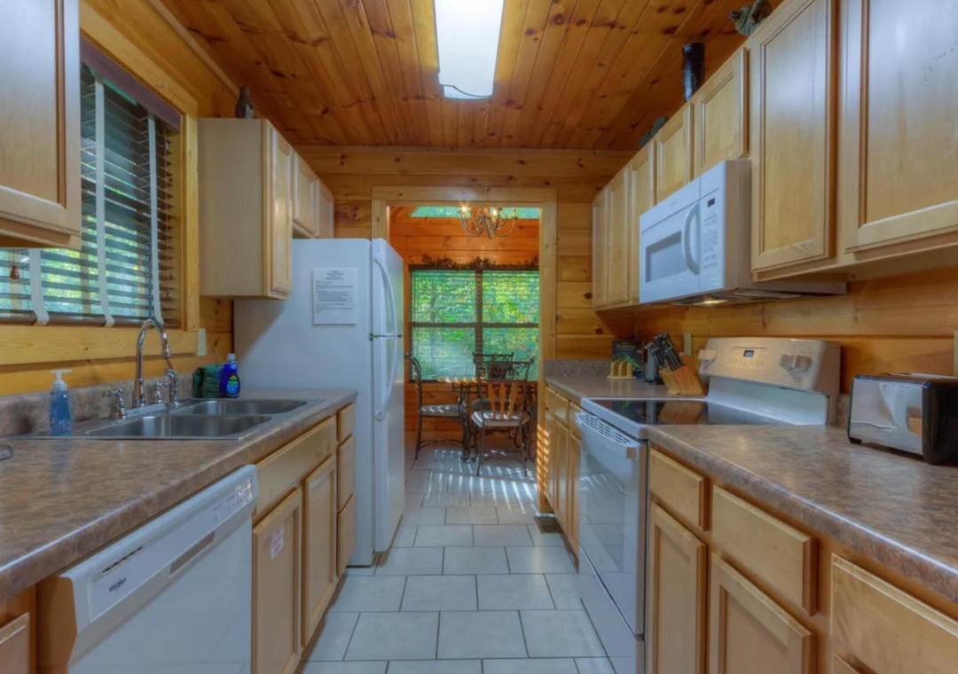 Your fully equipped kitchen features warm wood cabinetry, modern appliances, and ample counter space for preparing meals during your stay, with natural light streaming through the windows.