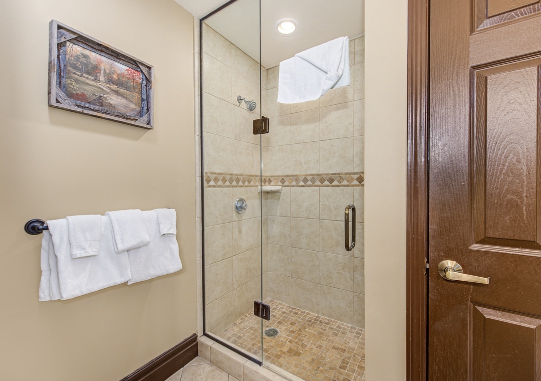 Step into your elegant glass-enclosed shower with beautiful tile work and fresh towels waiting for your arrival.