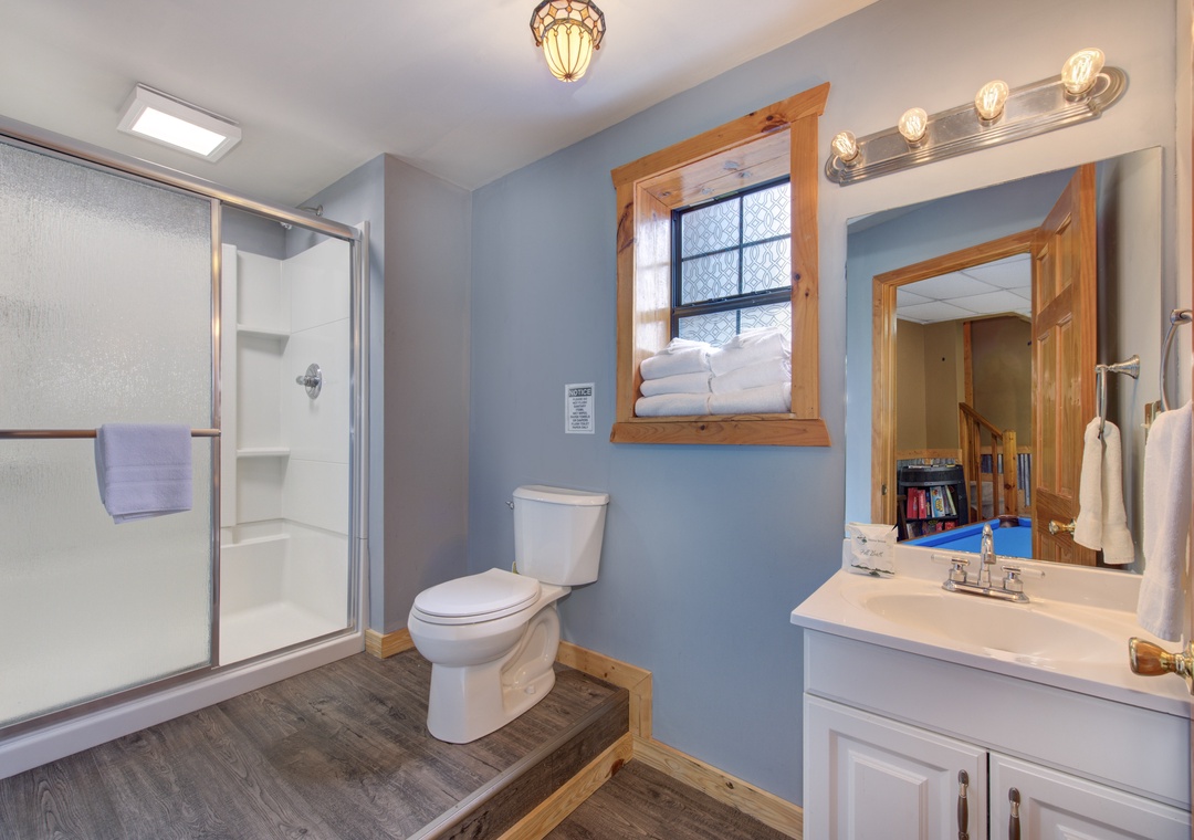 Refresh in your spacious bathroom featuring a glass-door shower, warm wood accents, and thoughtful amenities for a comfortable stay.