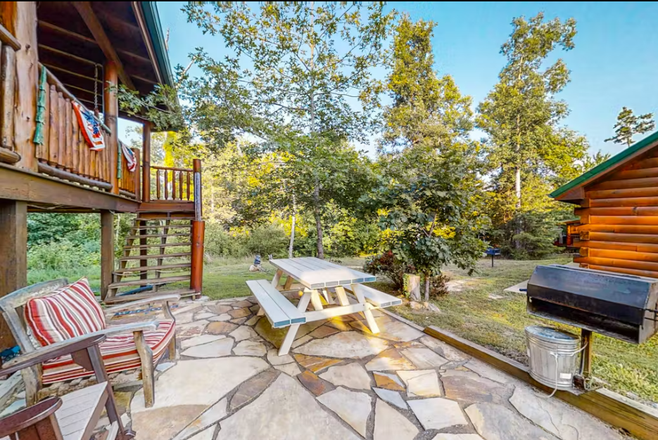 Relax on your private stone patio with comfortable seating, picnic table, and BBQ grill surrounded by mature trees.