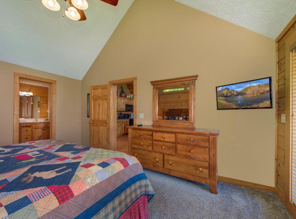 Relax in this cozy bedroom featuring rustic wood furniture, a TV for evening entertainment, and peaceful mountain views to inspire your mornings.