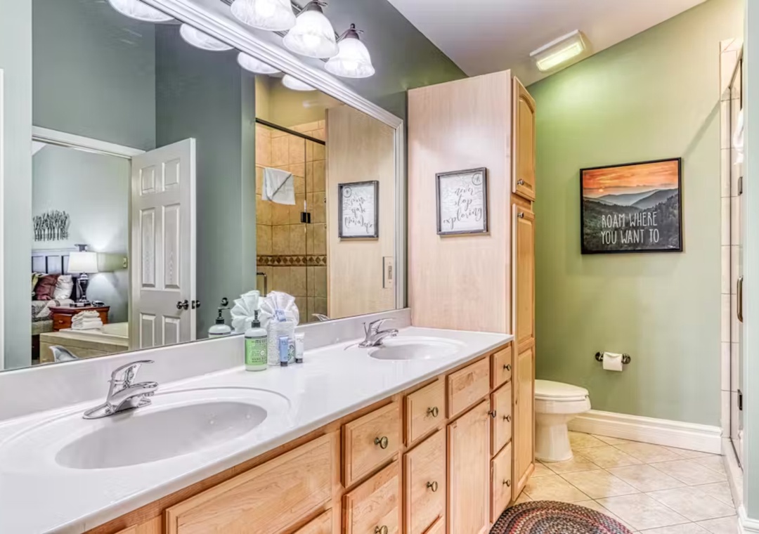 Relax in your private bathroom featuring dual sinks, warm wood cabinetry, and soothing green walls that create a spa-like retreat.