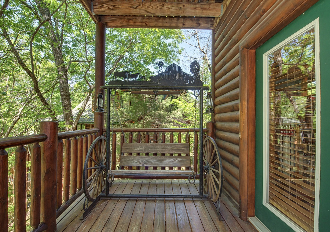 Relax on your rustic wagon wheel swing while enjoying peaceful forest views from your covered deck.