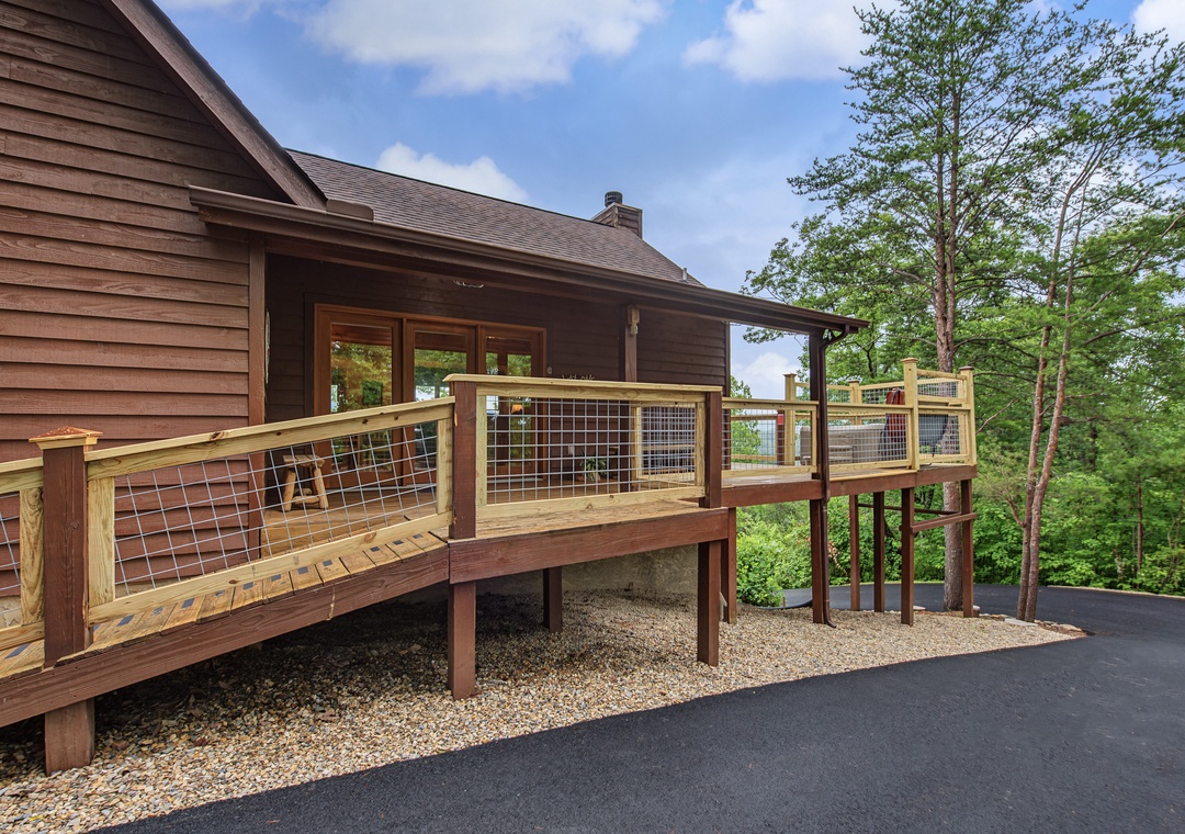 Modern mountain retreat featuring clean architectural lines and a spacious deck area, nestled among mature trees with ample parking and scenic wooded surroundings.