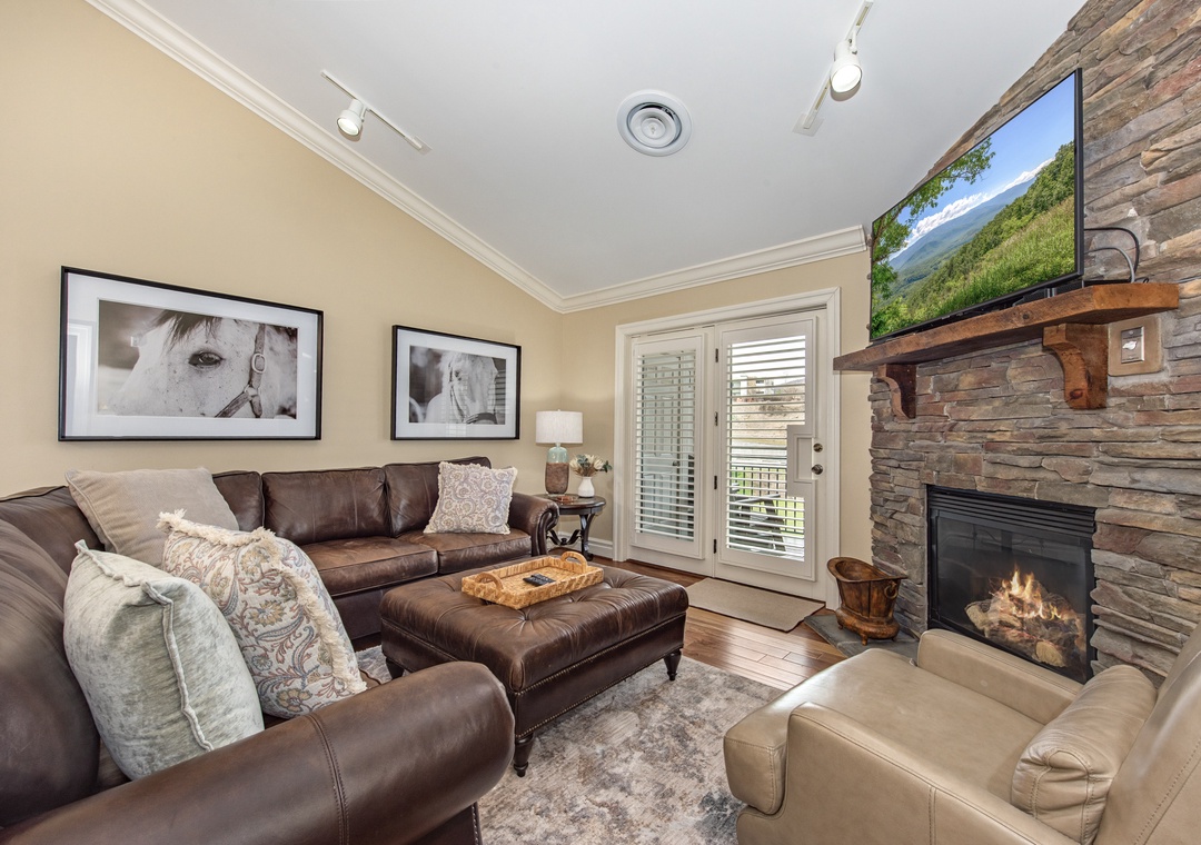 Unwind in your cozy living room with plush leather seating, a warm stone fireplace, and modern entertainment for perfect mountain evenings.