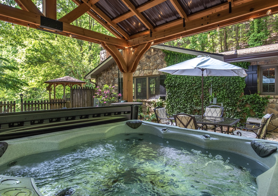 Slip into your private hot tub beneath a handcrafted timber pavilion, surrounded by lush forest greens and peaceful outdoor seating—your own tranquil escape.