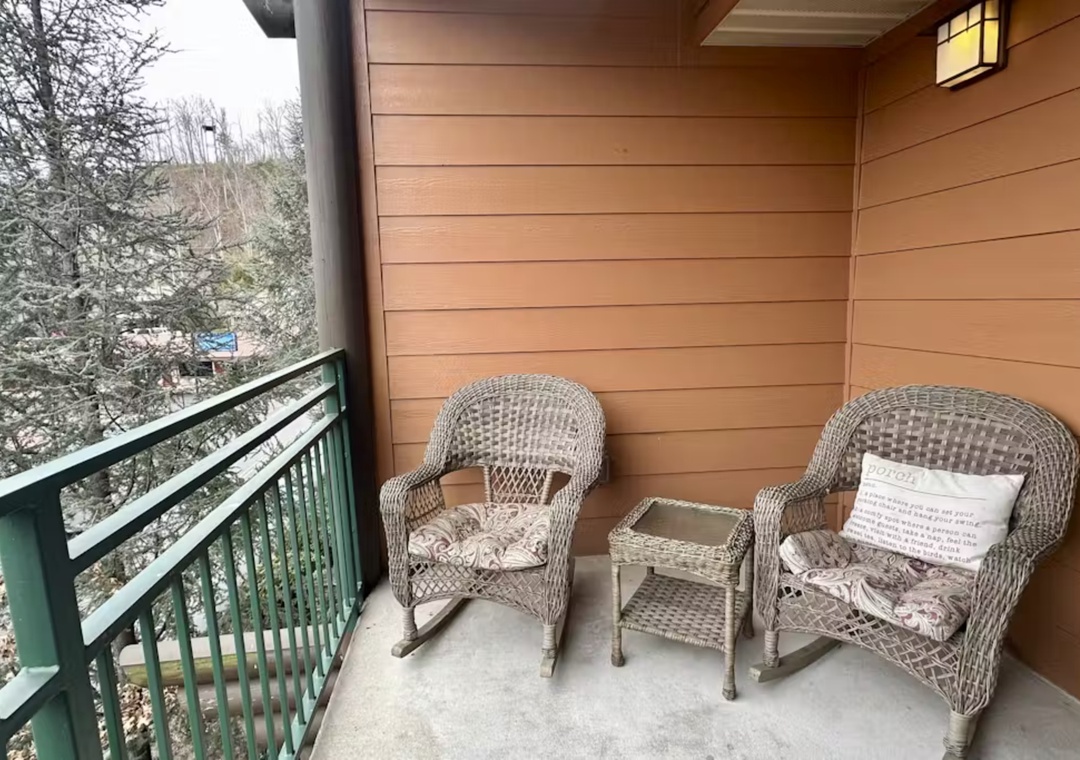 Unwind on your private balcony with comfortable wicker seating, perfect for morning coffee or evening relaxation overlooking the peaceful wooded surroundings.