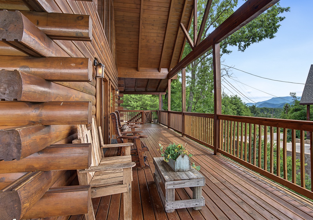 Charming log cabin porch with Adirondack seating and sweeping mountain views of the surrounding landscape and scenic area.