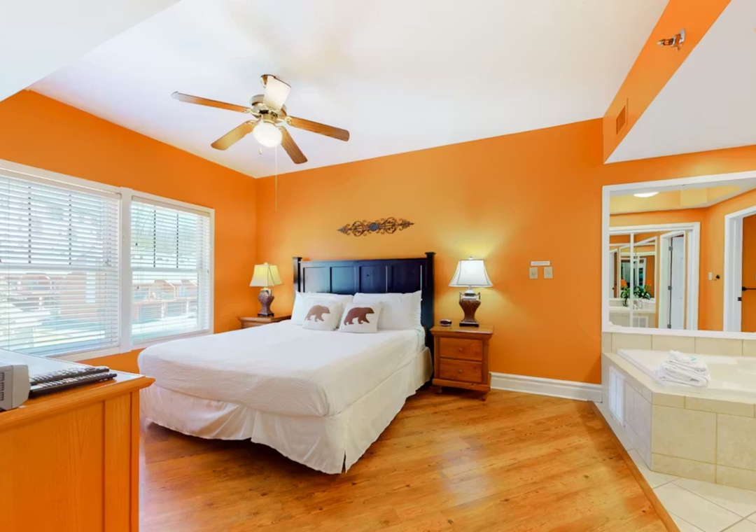 Relax in your vibrant orange bedroom with crisp linens, ceiling fan, and convenient jetted tub for ultimate comfort.