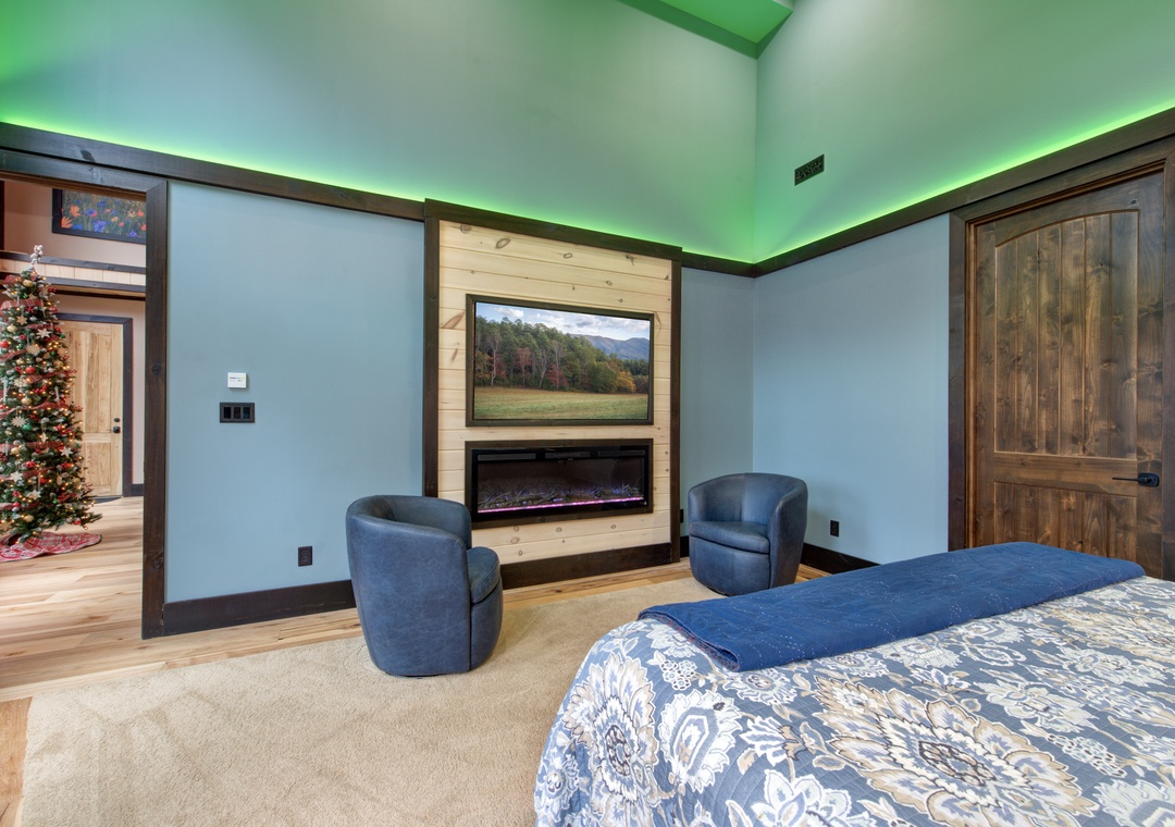 Unwind in your spacious bedroom featuring a cozy fireplace, comfortable seating area, and warm ambient lighting that creates the perfect atmosphere for relaxation.