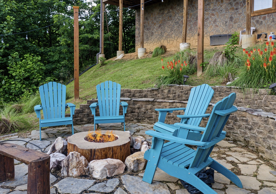 Gather around the warmth of the fire pit in these inviting blue Adirondack chairs, surrounded by lush gardens and natural stone terraces—a perfect spot to unwind under the open sky.